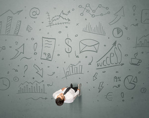 Young contemplating businessman stands in front of business graphics