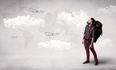 Handsome young man standing with a backpack on his back and planes in front of a world map as a background 