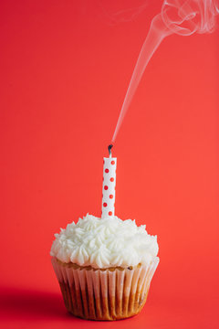 Birthday cupcake with smoking candle on a red background