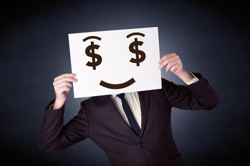 Young casual businessman hiding behind a greedy face drawing on cardboard