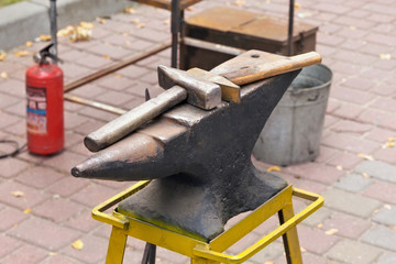 Hammers on the anvil in the street forge workshop.