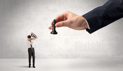 Little businessman is afraid to make the next step in his chess game with graphs, charts and...