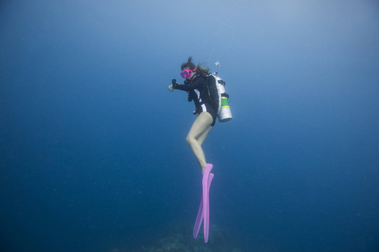 A young female diver floating and watching dive computer