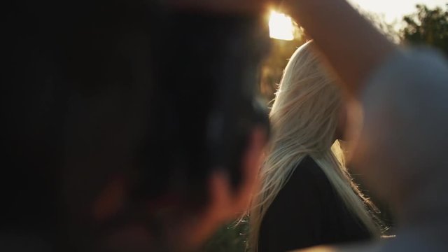 A close-up of a photographer shooting a beautiful blond girl outside