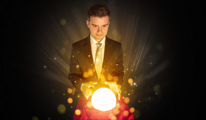 Gorgeous businessman sitting with sparkling magic ball in his lap
