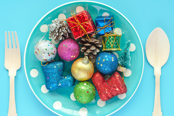 Polka dot plate of Xmas ornaments and decoration with wooden spoon and fork on blue background for Christmas day and holidays concept