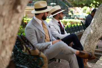 Two men dressed up sitting on a bench