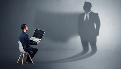 Humble businessman staying and offering stuffs to a huge businessman shadow

