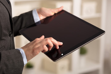 Business woman below chest using tablet in a homey environment
