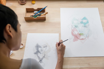 Beautiful artist sitting and painting at home