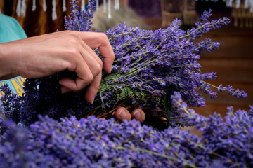 A woman's hands working with freshly harvested lavender flowers to make a lavender wreath. © just.b photography