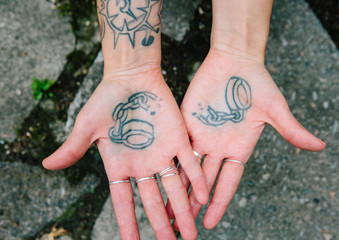 a tattoo of broken handcuffs on the palms of two hands