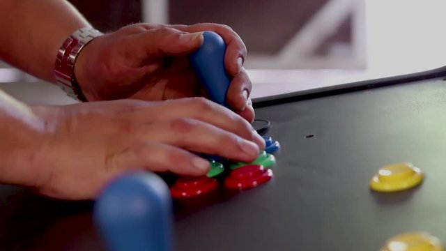 A SLOWMOTION side view close up shot of a man playing video game by controlling joystick and pressing various buttons with his hands
