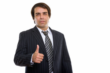 Studio shot of young Persian businessman giving thumb up