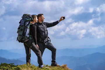 Tuinposter The happy couple with backpacks take a selfie on the cliff © realstock1