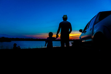 Father and son are playing on the lake at sunset. People have fun on the field. Family Friendly...