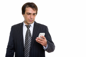 Studio shot of young Persian businessman using mobile phone