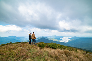 The happy man and a woman standing on the top of a mountain