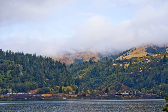 Landscape with Columbia River in the morning haze mountains and evergreens and houses on the hills in the Hood River