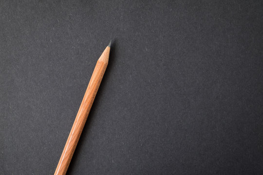 Top View Of Notebook Black Cover With Wood Texture Pencil On White Desk Background