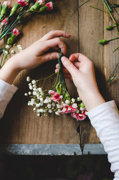 Hands of a child making a flower crown