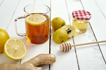 delicious hot tea with lemon on an old white wooden table with ginger and honey