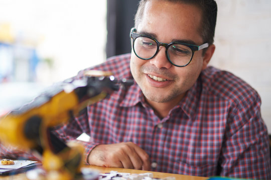 Young engineer with a model of an industrial robot