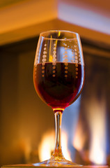 Glass with red wine in front of fireplace