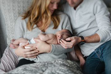 Happy new family of three cuddling in the bed together at home