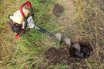 Worker drills the ground for the fence