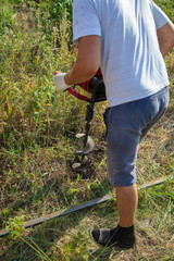 Worker drills the ground for the fence