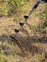 Worker drills the ground for the fence