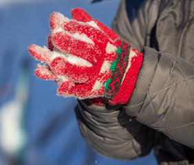 Gloves on the hands of a boy in the snow in winter