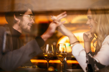 Side view of couple holding hands dining in restaurant.