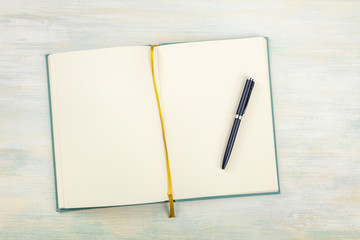 A top shot of an open journal with a pen on a light background with a place for text