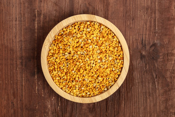 Healthy organic food. Bee pollen, shot from the top in a wooden bowl on a dark rustic background with copyspace