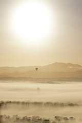 Obraz na płótnie Canvas Hot air balloon in misty mountains during sunrise