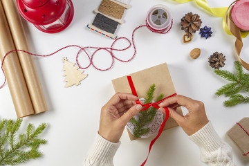 Christmas gift wrapping. Woman's hands packing Christmas presents on white table