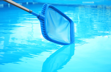 Cleaning outdoor pool with scoop net, closeup