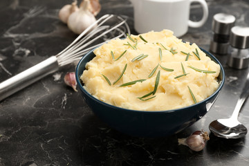 Bowl with tasty mashed potato on dark table