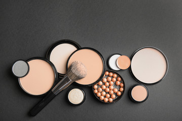 Flat lay composition with various makeup face powders on black background. Space for text