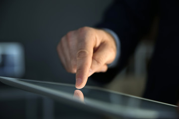 Businessman using digital tablet at workplace, closeup of hand. Mockup for design