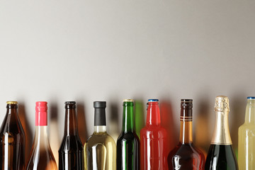 Bottles with different alcoholic drinks on light background, top view. Space for text