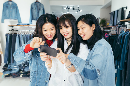Girlfriends taking selfie in clothing store
