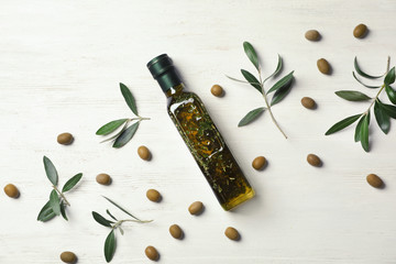 Flat lay composition with bottle of olive oil on white wooden background