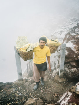 Laborer carrying loaded baskets with mineral
