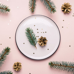 Christmas natural table setting. White plate and confetti on pink background