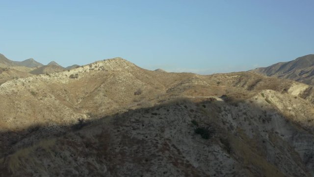 Aerial reveal of a barren mountainous landscape in the desert.