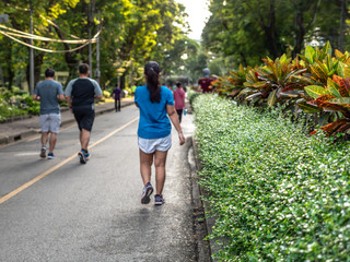 Selective focused on foreground at pathway with emotion blurred background. Rear view of people who are walking and running in public park. Low selection view of the way forward.