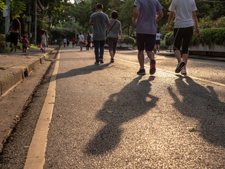 Selective focused on foreground at pathway with emotion blurred background. Rear view of people who are walking and running in public park. Low selection view of the way forward.